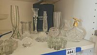 Wide photo showing entire lot of crystal and glass items including vases, candle holders, and the dispenser bottle on a shelf