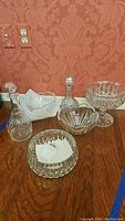 Overview of crystal decanters, bowls and serving dishes arranged on wood surface against red wallpaper.
