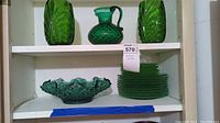 Shelf with a textured green glass bowl with scalloped edges and stacked green patterned glass plates.