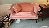 Front view of the rose-coloured velvet sofa in room setting