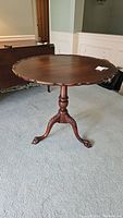 Full front view of round tilt-top table on pedestal base