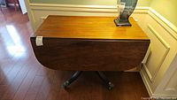 Closed top view of vintage wood drop leaf table with wood grain and lamp on top