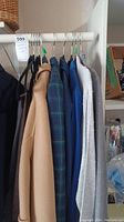 Multiple women's coats and jackets hung on a rack, different shades including beige and blue, showing overall lot contents.
