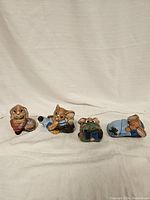 Four ceramic bunny figurines arranged in a row, showing distinct facial features, colors, and poses.