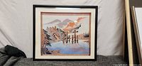 Framed Bunka embroidery depicting a lake with torii gate, pagoda, and mountain background in warm tones