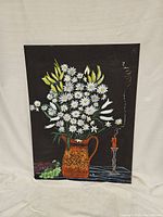 Full view of hand painted daisy jug canvas on black background with candle and grapes.
