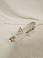Side view of white porcelain Victoria China shoe figurine decorated with pink and green floral patterns and gold trim.