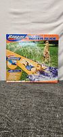 Front of the box showing the product name, brand, and an image of children playing on the water slide.