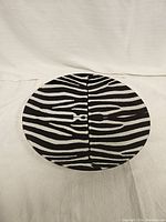 Top-down view of the round glass plate showing the black and white zebra stripe pattern and the symmetrical design.