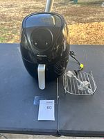 Front view of black PowerXL air fryer on table with metal rack and power cord visible.