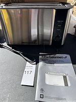 Stainless steel Elite Gourmet 4-slice long toaster with power cord, control knob, function buttons and instruction manual.