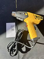 Yellow and black Wagner heat tool with power cord coiled beside it, lying flat on a surface with sunlight casting shadows.
