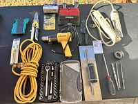 Full view of various tools and accessories spread out on a black surface in natural light.