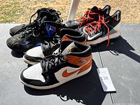Three pairs of Nike sneakers and basketball shoes placed outdoors on a surface, showing overall condition and design