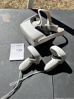 Oculus VR headset with two white wireless controllers arranged on a dark surface outdoors.