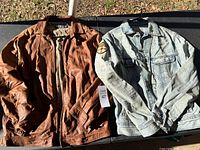 Both jackets laid flat on outdoor surface, showing overall lot contents and color contrast
