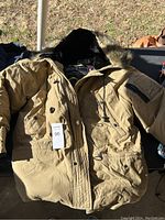 Front view of a medium brown Ralph Lauren RL Polo Jeans Co. winter coat with black faux fur hood lining, button and zipper pockets visible.