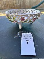 Side angle showing the lattice design and hand-painted pink and white roses with green leaves on the porcelain basket dish.