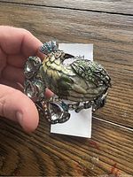 Top view of peacock design on bracelet, showing colored rhinestones in green, yellow and blue.