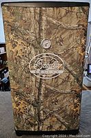 Front exterior view of smoker with camouflage cover and Bradley logo