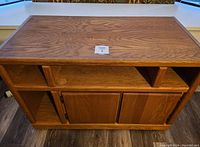 Front and top view of solid wood TV stand with open shelves and closed cabinet doors below.