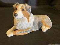 Front angled view of the Sandicast Australian Shepherd figurine showing detailed dog face and fur textures in multiple colors including white, brown, and grey.