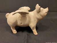 Side view of cast iron pig bank showing one wing and detailed features of the pig.