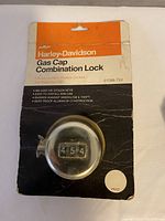 Unopened Harley-Davidson gas cap combination lock in original packaging, packaging shows creases and dirt.