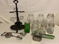 Full lot image including cast iron hand towel stand, vintage glass jars, manual hand mixers, and kitchen ricer on white background