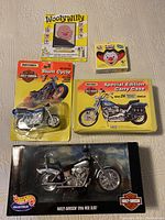 Full lot of 5 toys arranged on white surface: Wooly Willy, Bozo Kazoo, Matchbox Motorized Stunt Cycle, Matchbox Carry Case, Hot Wheels diecast bike