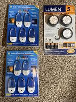 Two unopened packs of 5 color changing night lights and one unopened pack of 3 wireless LED puck lights in original retail packaging.