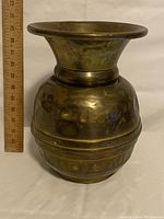 Side view of the brass spittoon with a ruler to show height approximately 32 cm.