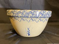 Front view of the ceramic mixing bowl showing the blue wheat design and decorative blue rim pattern on beige background.