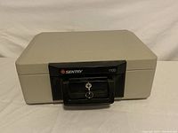 Closed view of the Sentry 1100 fire safe chest showing the locking handle and key inserted