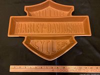 Top view of terracotta serving platter shaped like Harley-Davidson Bar & Shield with raised text.