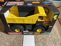 Side view of the Tonka Mighty Dump truck in original box, showing the truck and the worn condition of the box with tears and scuffs.