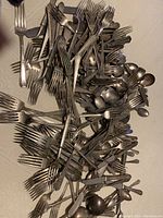 Large pile of mixed used forks and spoons, some bent and scratched.