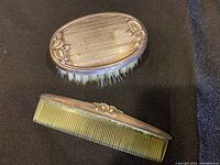 Close-up of sterling silver baby brush with nylon bristles and matching comb showing ornate floral design