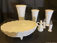Photo showing the three white milk glass vases with grape pattern, the oval footed bowl, small milk glass pitcher with stopper, and the shaker set.