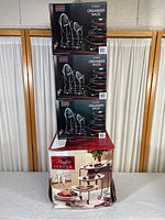 View showing stacked three boxes of Seville Classics 2-pack organizer racks and one box of buffet server on bottom with visible box damage.