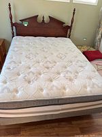 Full view of double bed showing mattress, box spring and wooden double headboard with turned posts.