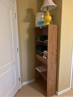 Two wooden bookshelves stacked vertically in corner of room with books and phone on shelves.