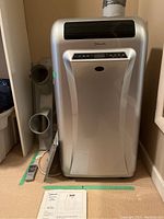 Front view of Danby Silhouette portable air conditioner with owner’s manual on floor