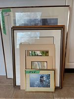 Several framed artwork pieces stacked together showing size range and framing styles
