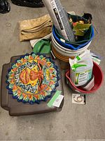 Overall view of buckets, gardening and painting supplies, side tables and decorative wall hanging stacked together