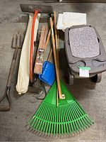 Full view of garden tools, vapor barrier roll, and garden scooter with cushioned seat