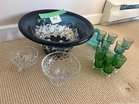 Wide view of all glass items on carpet showing decorative bowl, two sets of shot glasses, small glass bird, and two dishes