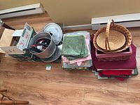Wide shot showing metal pots, utensils, stacks of colorful fabric placemats, and woven baskets.