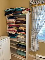 Photo of the white bookcase filled with various folded fabrics in multiple colors and patterns.