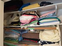 Shelves with multiple folded fabric pieces of assorted colors including blue, cream, yellow, and patterned fabrics.